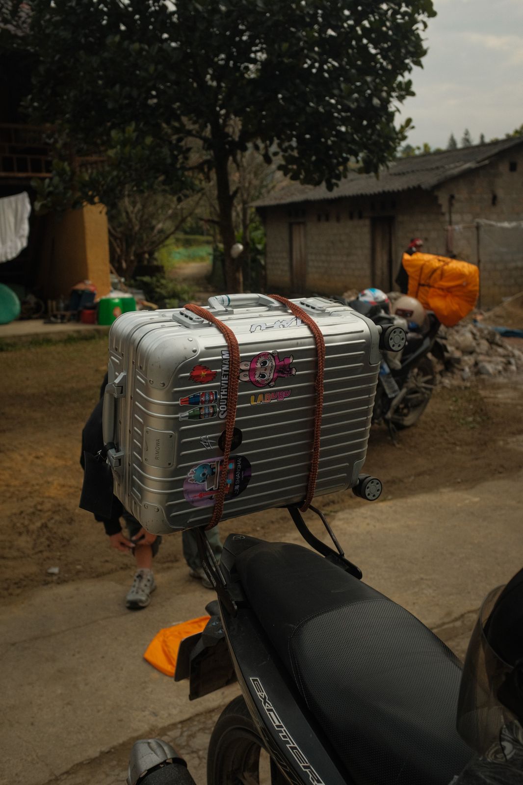A silver suitcase strapped to the back of a scooter in Vietnam