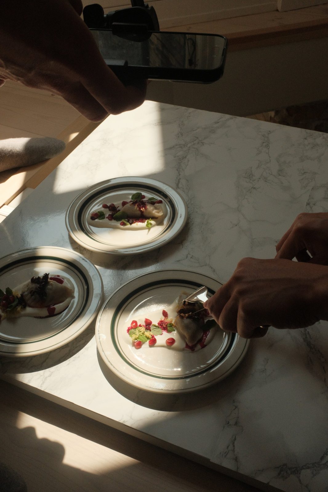 Plating dumplings on the shoot, with a phone filming from above